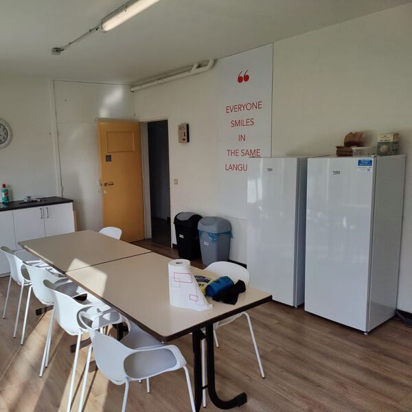 A kitchen area with a table and chairs, two refrigerators, and a countertop with a sink...